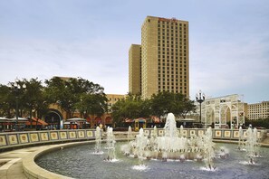 A hotel with a prominent Hilton sign, a fountain in the foreground, and surrounding urban buildings. - Hilton New Orleans Riverside (New Orleans)