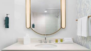 A bathroom with a white sink, a mirror with a gold frame, a towel rack, and toiletries on the counter.