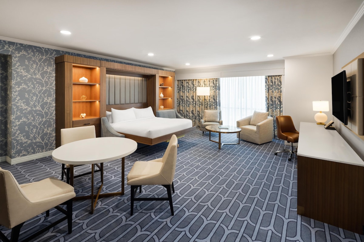 A hotel room with a bed, a desk, a chair, a round table, and a sofa.