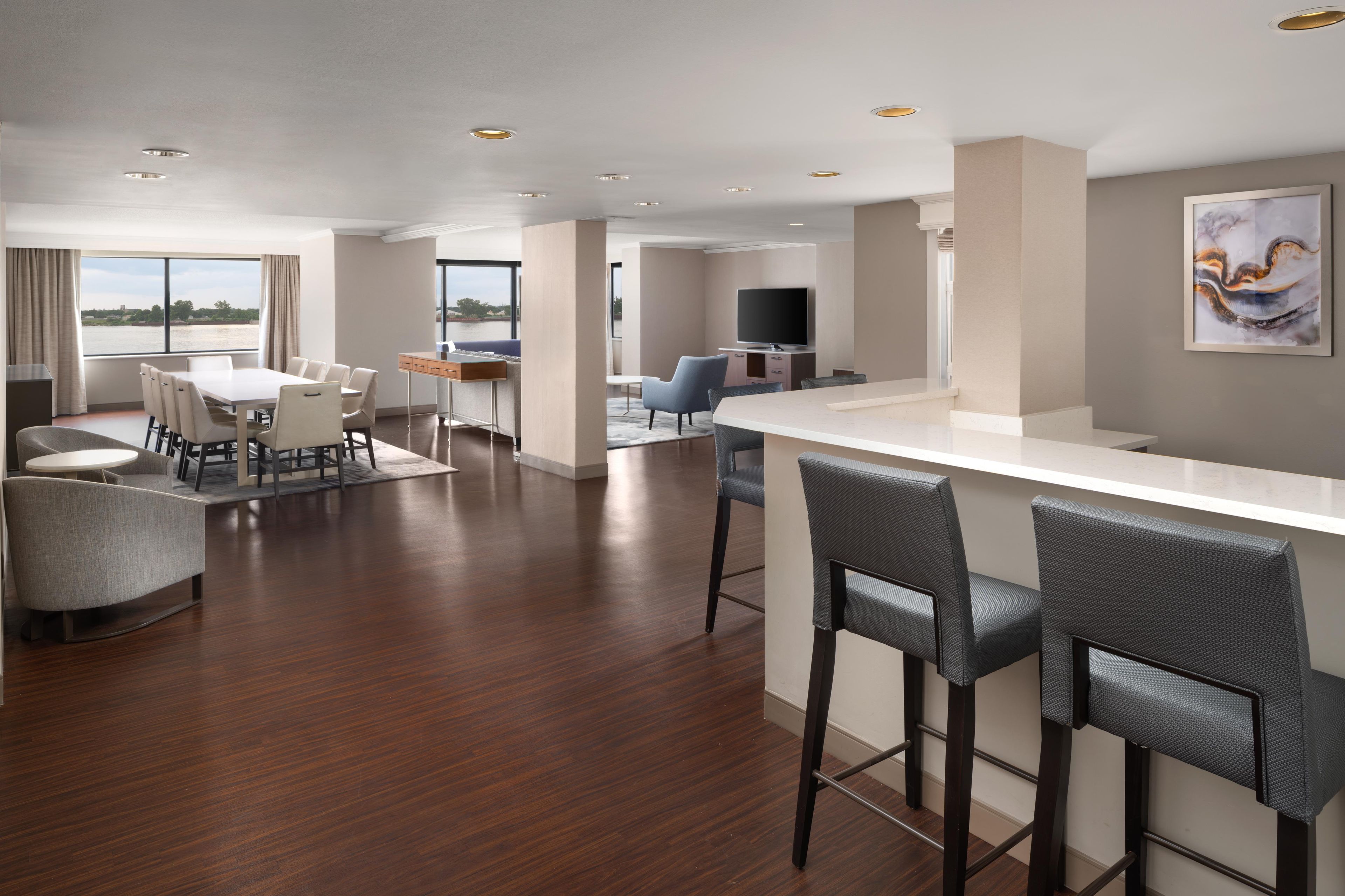 A modern hotel room with a dining area, a bar, and a TV.