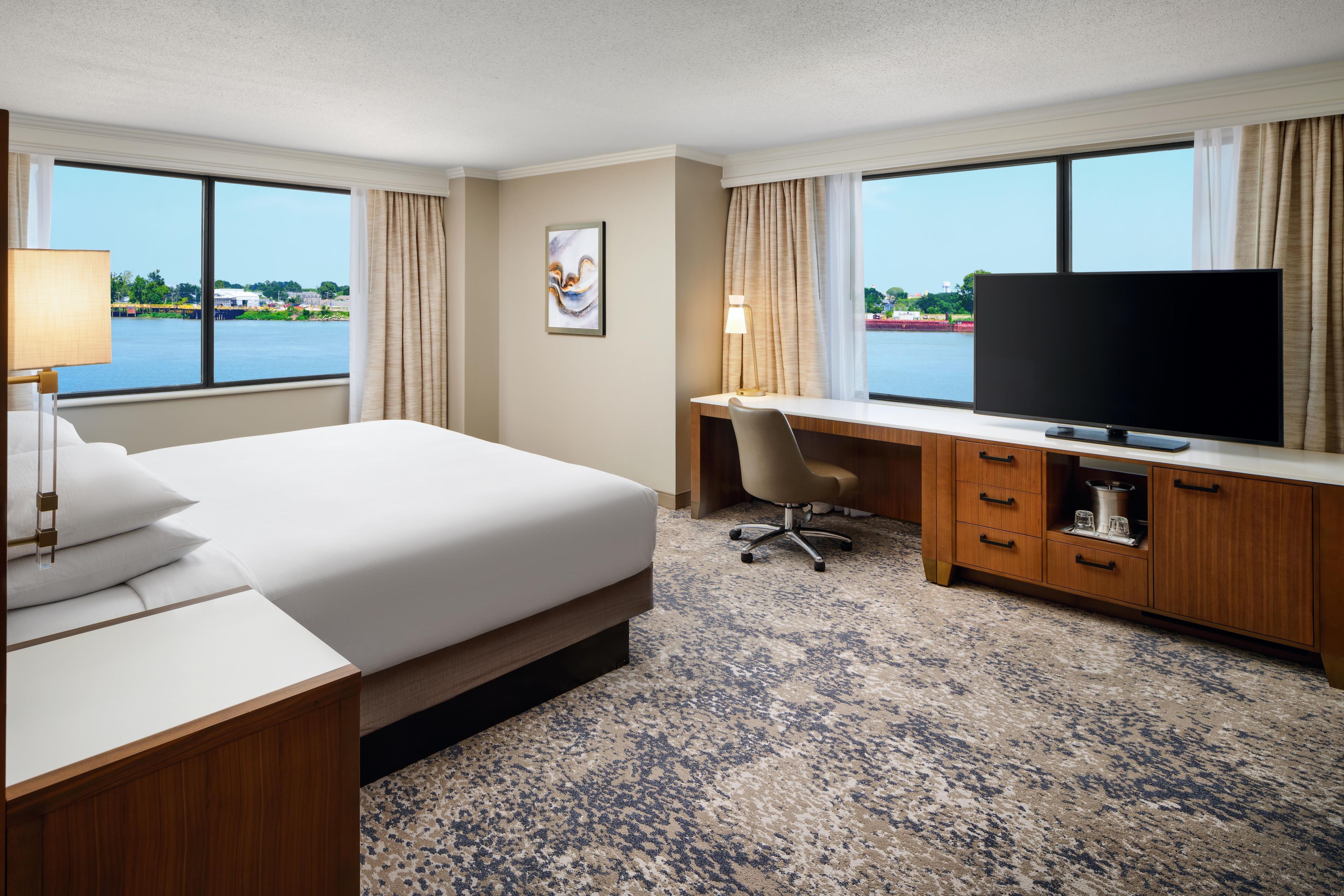 Une chambre d’hôtel avec un lit, un bureau, une télévision et une vue sur une étendue d’eau.