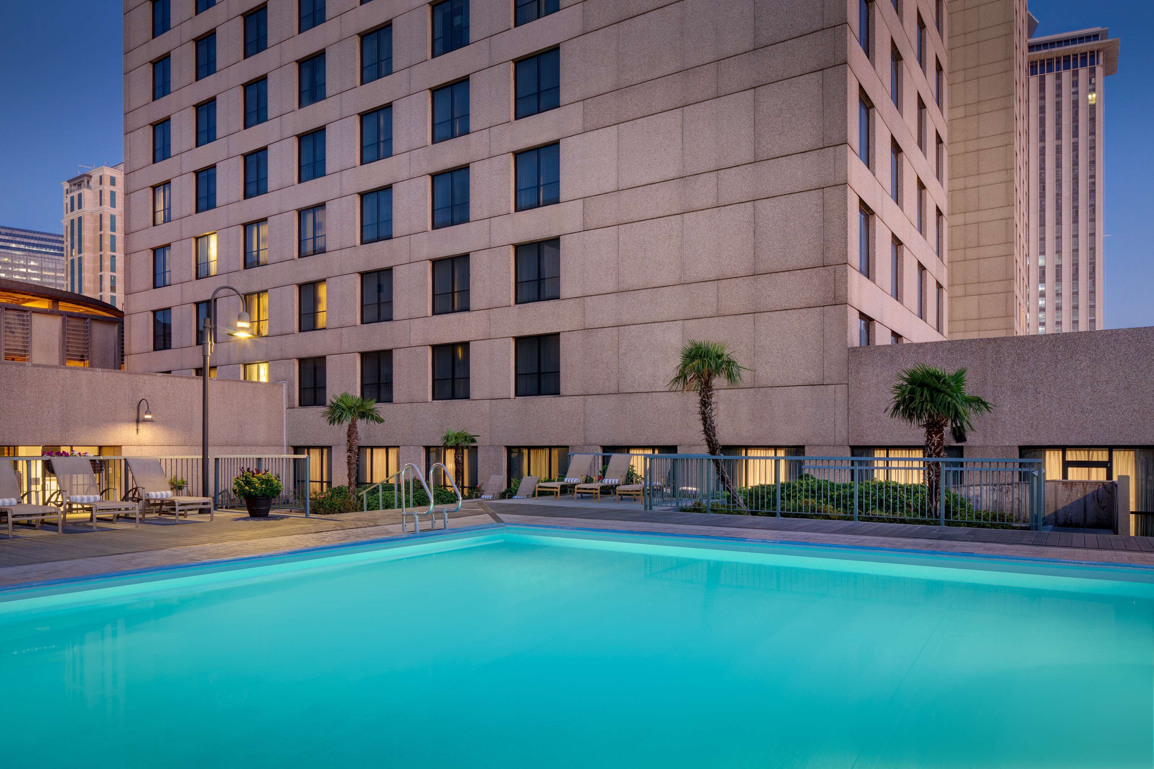 Un hôtel moderne doté d’une piscine, de plusieurs étages et d’une façade bien éclairée.