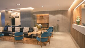 Un espace de détente moderne comprenant un ensemble de canapés, des fauteuils et un comptoir d’accueil.