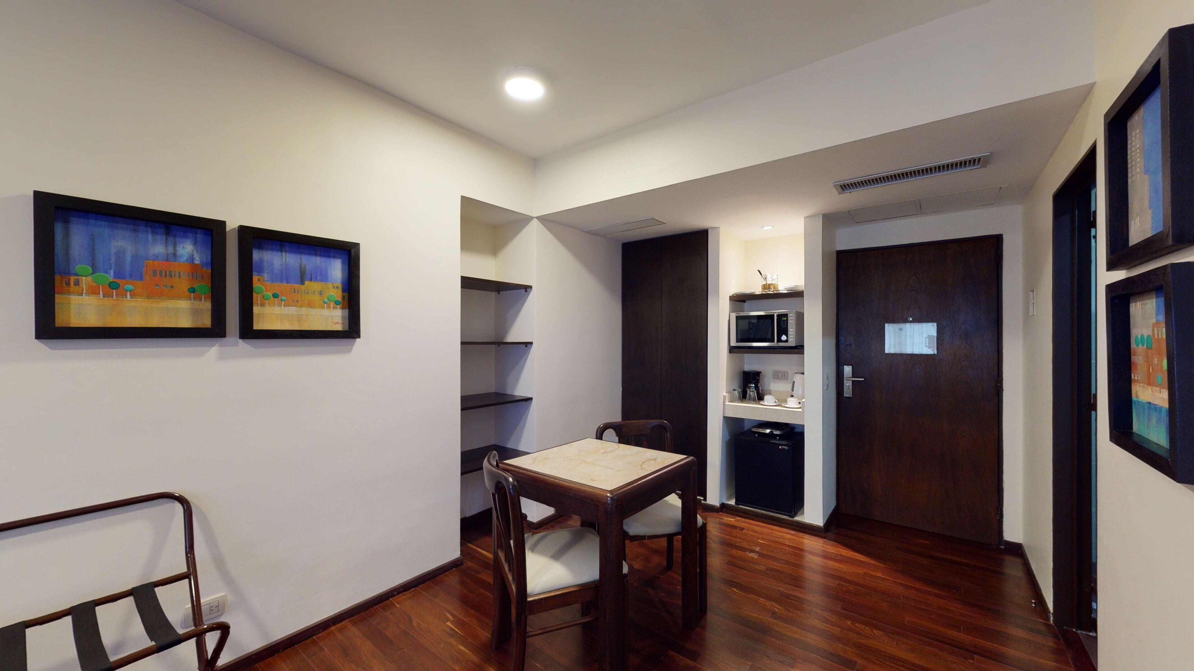 A room with a dining table, chairs, a microwave, and a door with a sign.