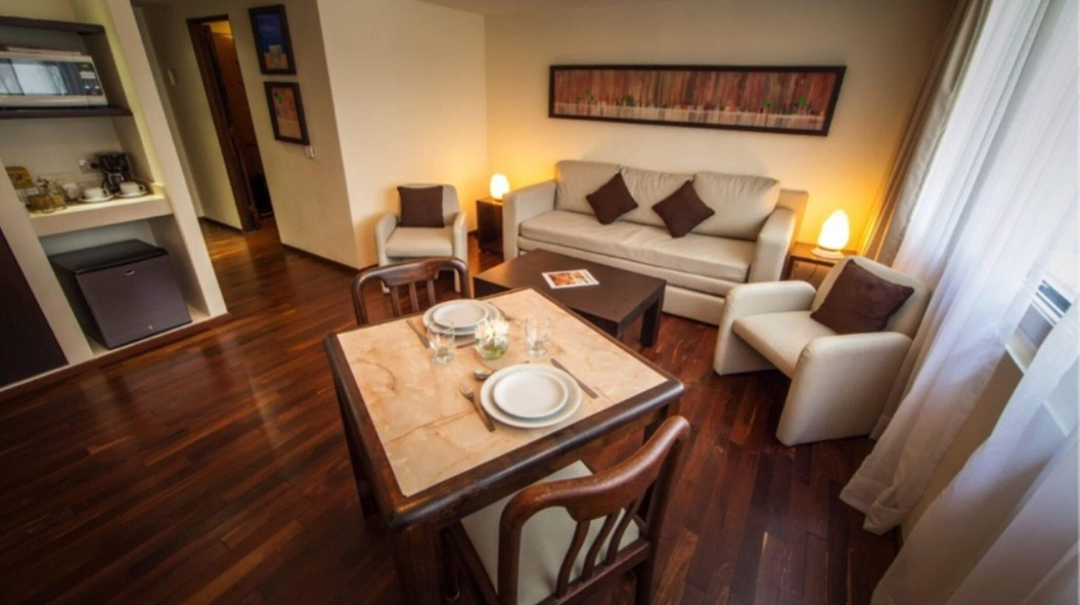 Habitación de hotel con zona de comedor, sofá, cafetera y microondas.