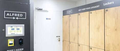 Zona de almacenamiento de equipaje con taquillas numeradas y un cartel que pregunta: ¿PUEDO GUARDAR SU EQUIPAJE?