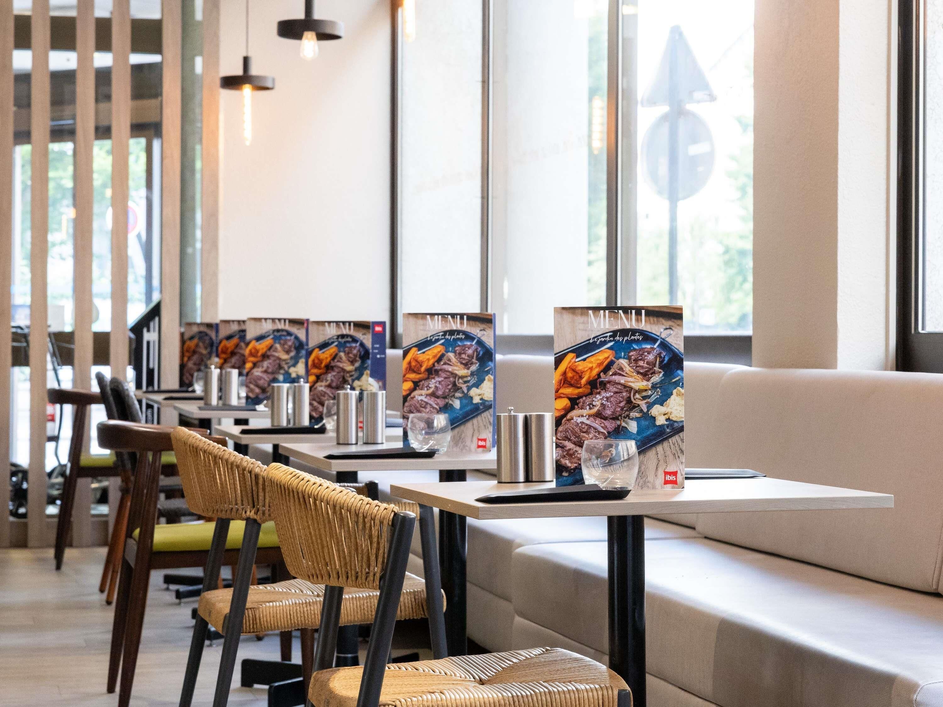 A restaurant interior with wicker chairs, tables, and menu boards displaying food images.