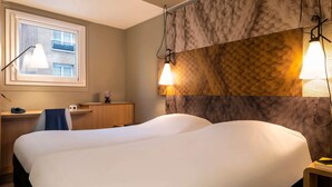 A hotel room with a large bed, a desk, a chair, and a window with a view of buildings. - ibis Paris Alésia Montparnasse 14ème (Paris)