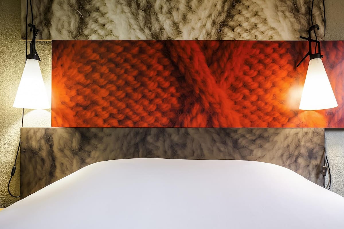 Une salle de bain moderne avec un grand miroir, deux lampes suspendues et un mur Ă texture.