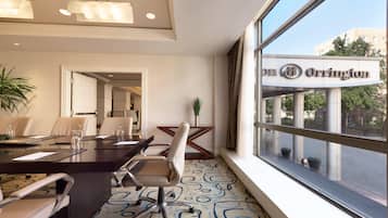A conference room with a large table, chairs, and a view of the city through large windows.