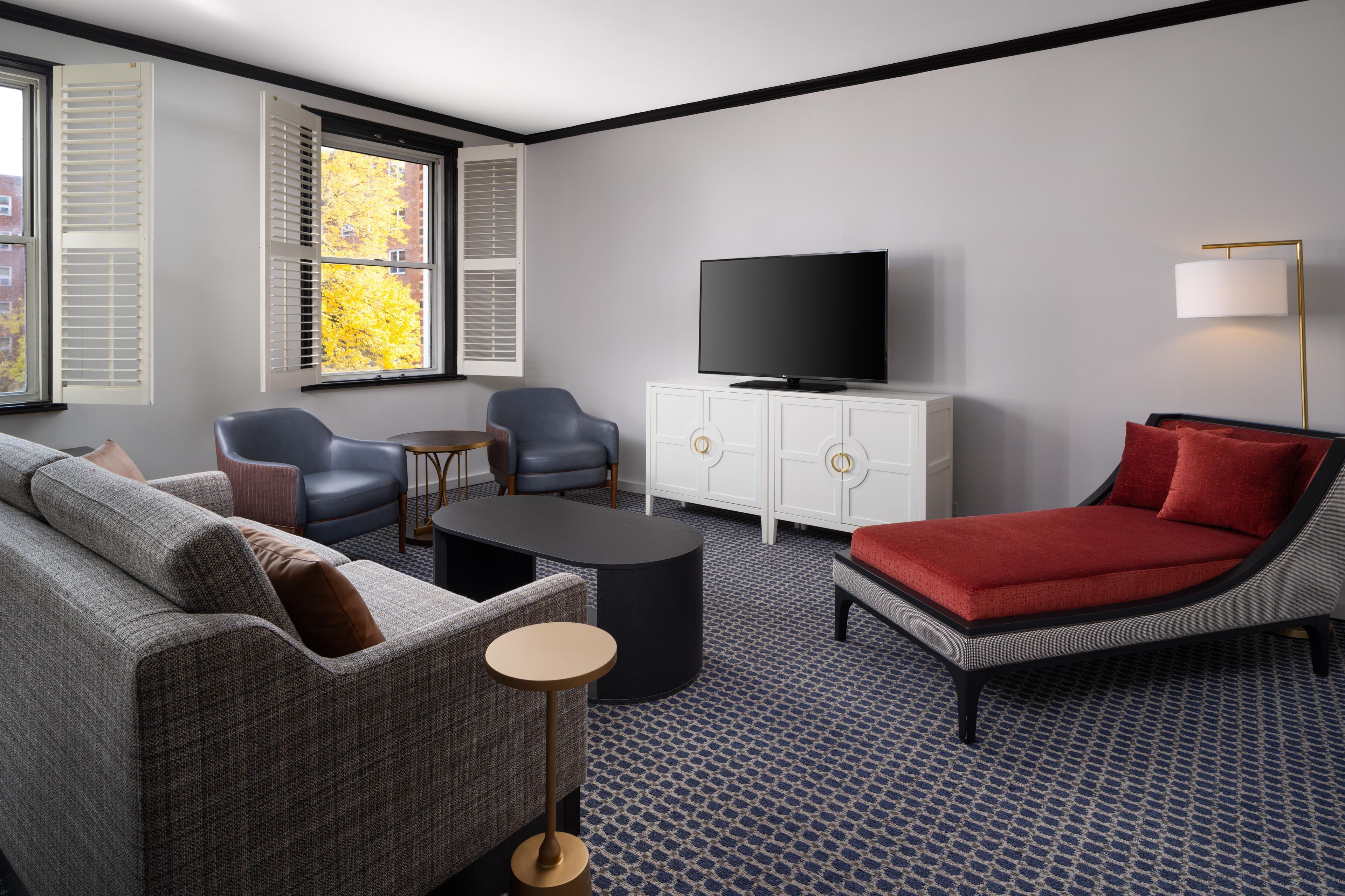 Una sala moderna con sofá, sillones, una mesa de centro, televisor y aparador.