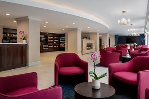 Un vestíbulo de hotel con zona de estar, minibar y televisión.