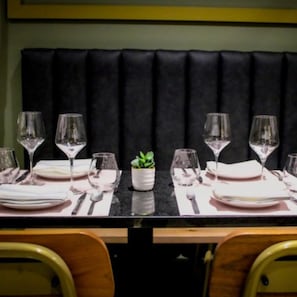 A dining table set with plates, cutlery, and wine glasses, flanked by wooden chairs. - Hilton Orrington / Evanston (Evanston)