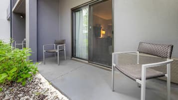 Een balkon met een stoel, een tafel, een schuifpui en een plant.
