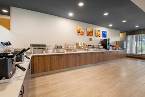 A modern breakfast bar with self-service stations, a coffee machine, and a large window with a view.