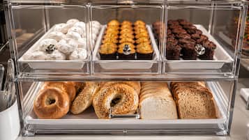 A bakery display case with various baked goods including pastries, muffins, and bagels.