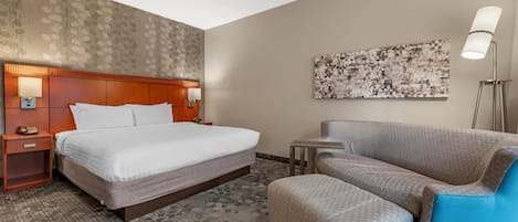 A hotel room with a bed, a nightstand, a desk, a chair, and a floor lamp.