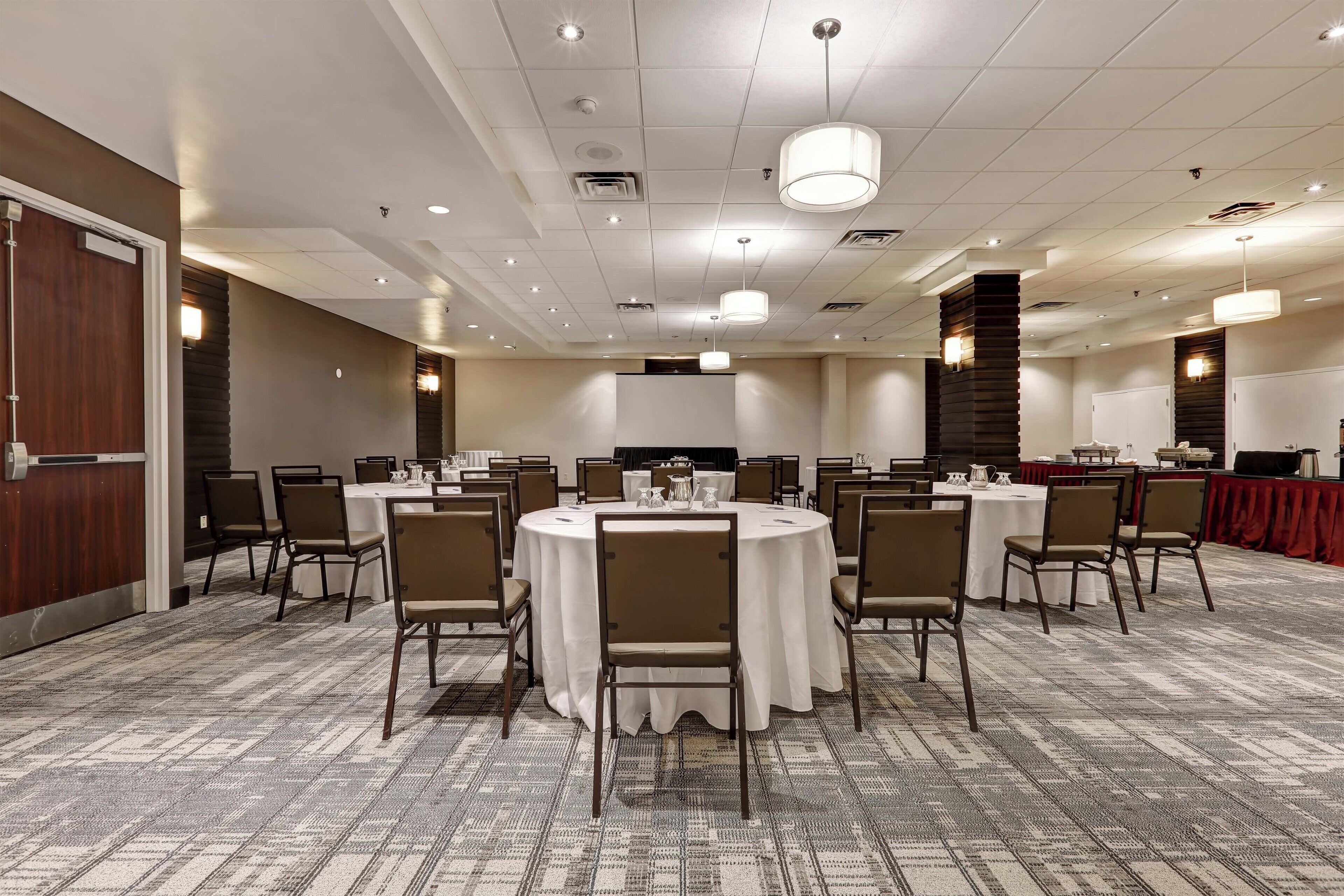 A conference room with round tables, chairs, and a patterned carpet.