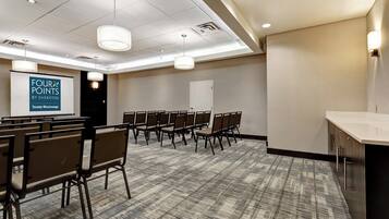 A conference room with rows of chairs, a projection screen, and a kitchenette area.