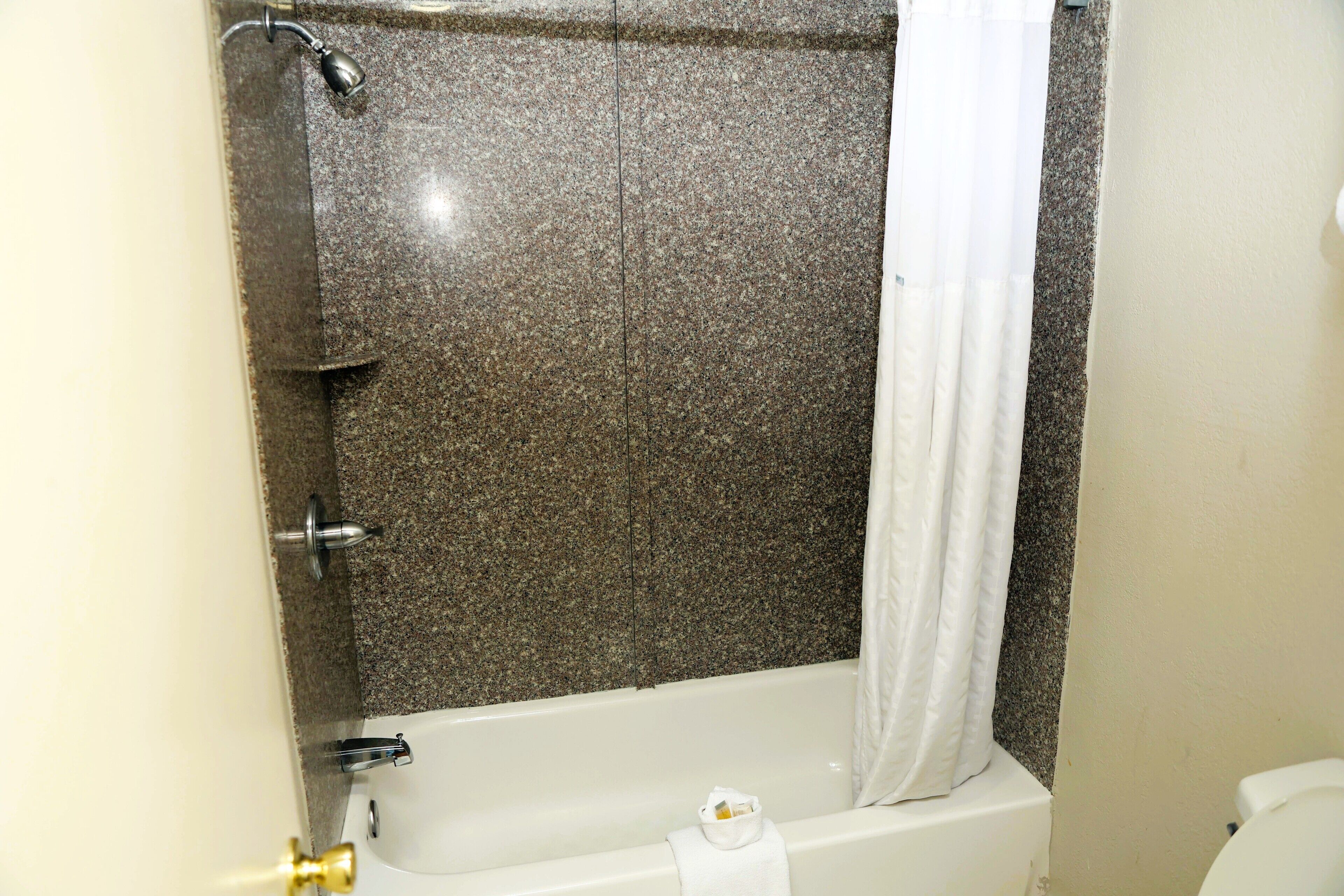 A bathroom with a bathtub, shower, and toilet.