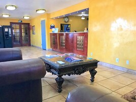 A lobby with a reception desk, a clock, and a coffee table with magazines.