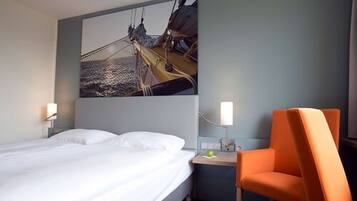 A hotel room with a bed, a nightstand, a chair, and a large painting of a ship on the wall.
