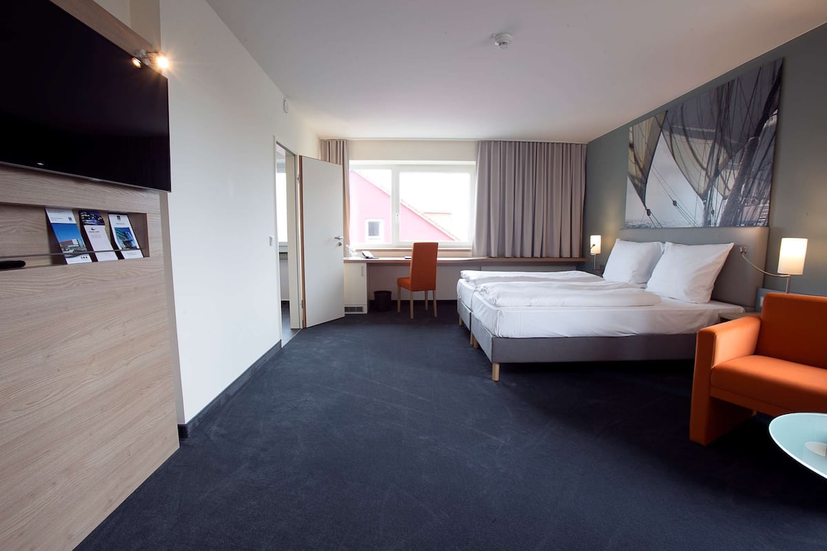 Una habitación de hotel con cama, escritorio, silla y televisor.