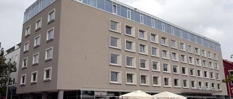 A modern hotel with a flat facade, multiple windows, and outdoor seating area.