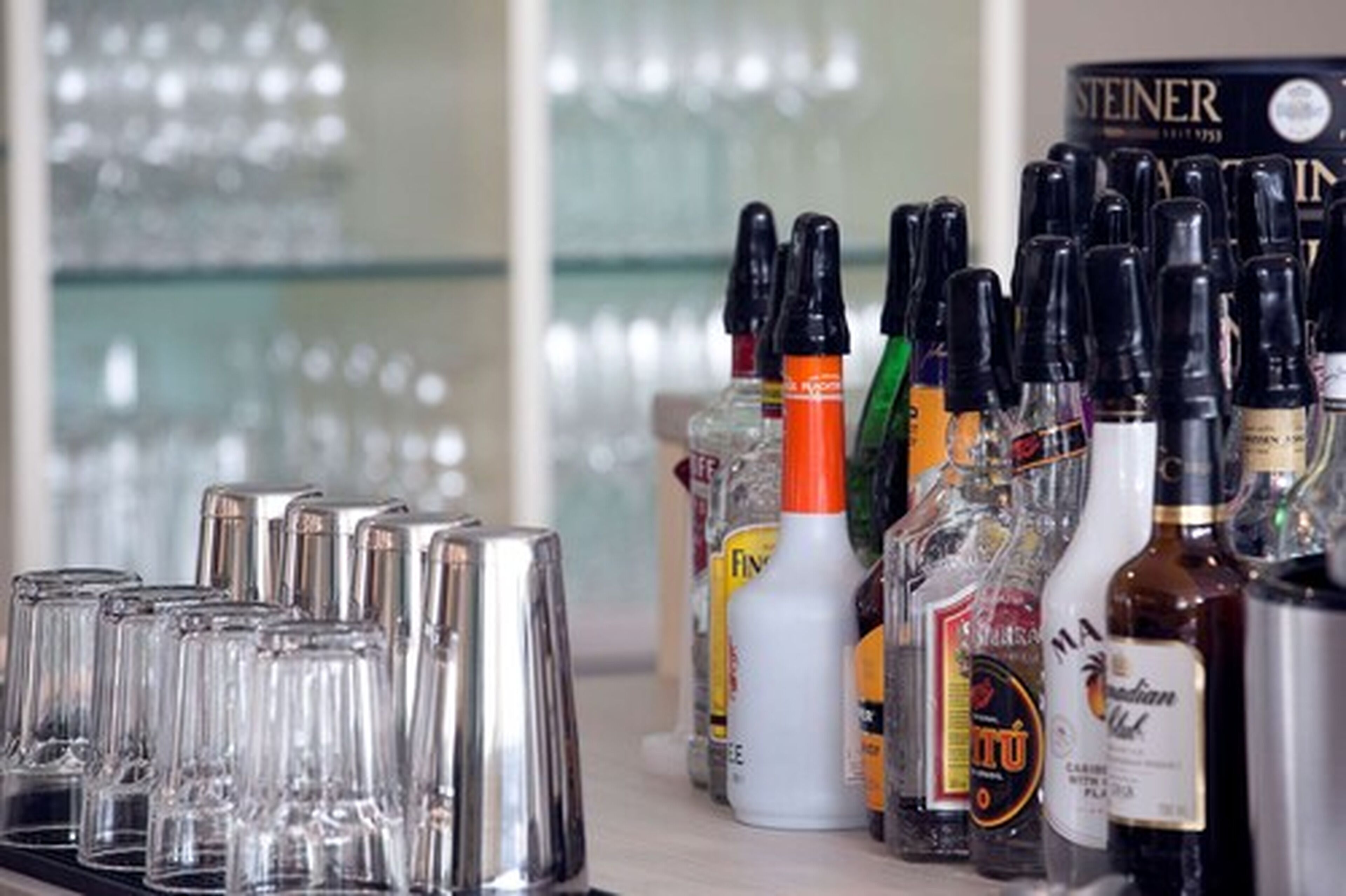 A bar area with various bottles of liquor and a row of empty glasses.
