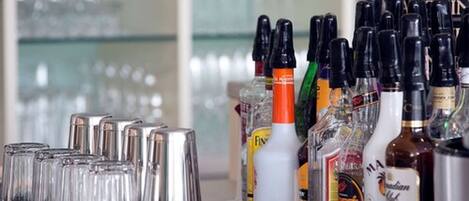 A bar area with various bottles of liquor and a row of empty glasses.