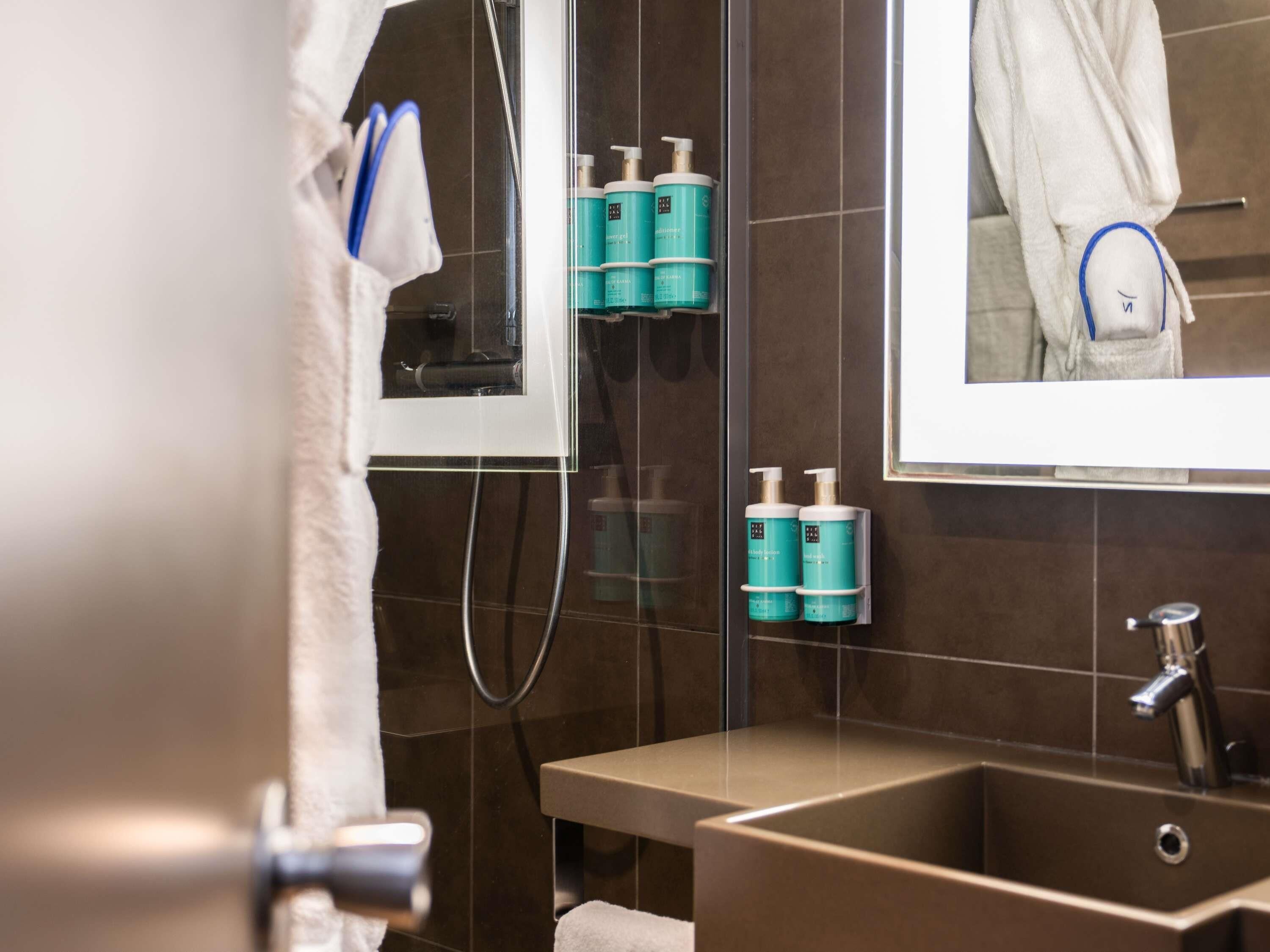 Un baño moderno con un espejo grande, un lavabo y dos dispensadores de loción corporal.