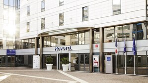 A Novotel hotel with a modern facade, large windows, and a covered entrance area. - Novotel Paris Rueil Malmaison (Rueil-Malmaison)