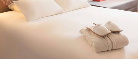 A neatly made bed with pillows and a folded towel.