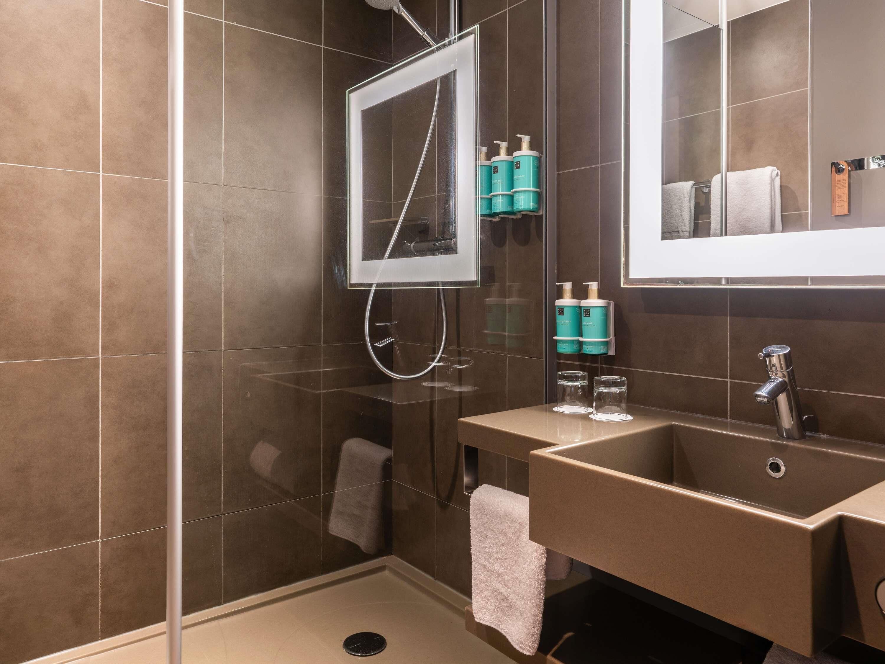 A modern bathroom with a shower, a sink, and a mirror.