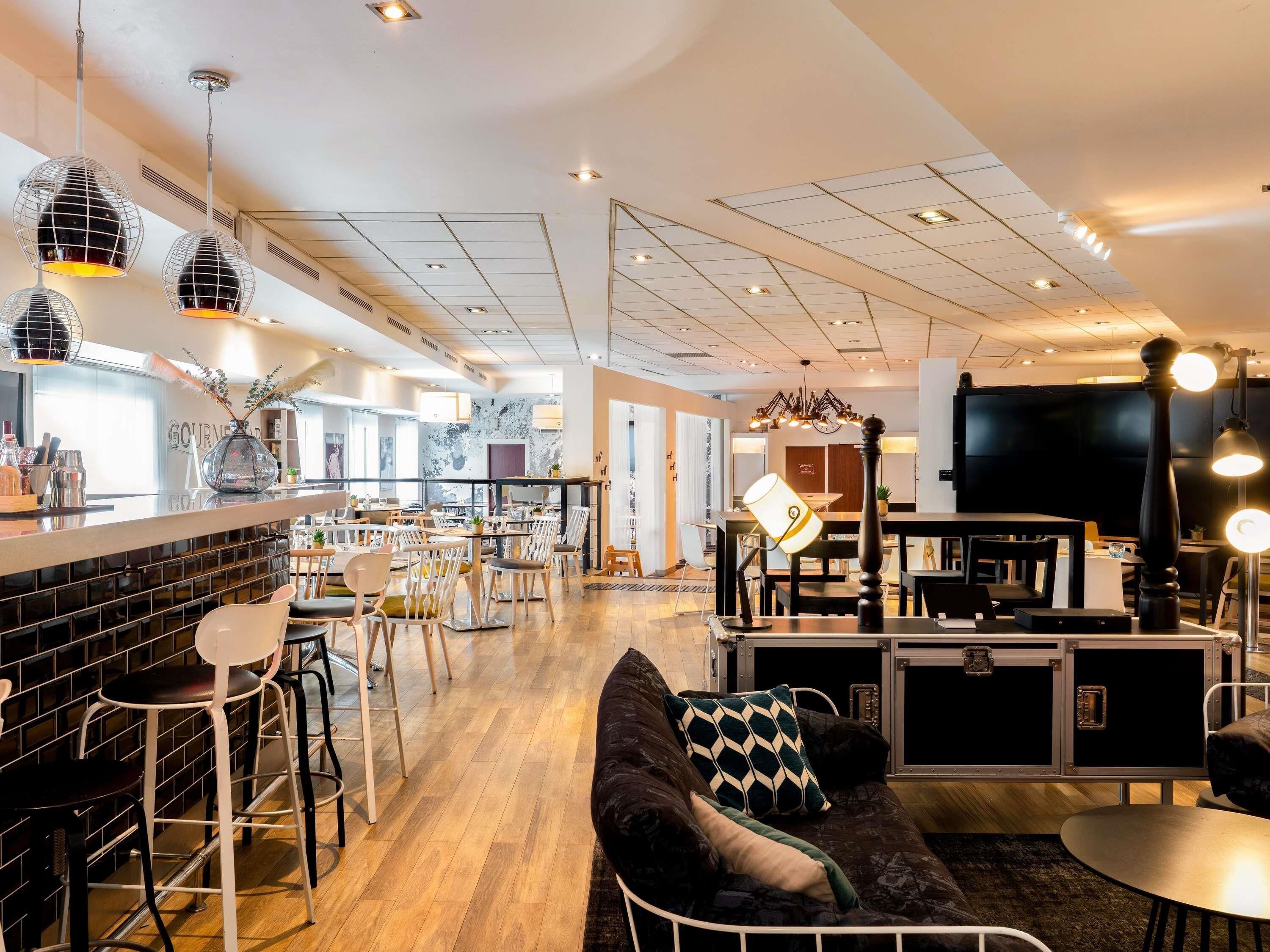 Un intérieur moderne avec un bar, des sièges et un téléviseur.