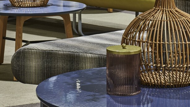 A modern living room with a sofa, ottomans, and two wicker vases with flowers. - Novotel Paris Rueil Malmaison (Rueil-Malmaison)
