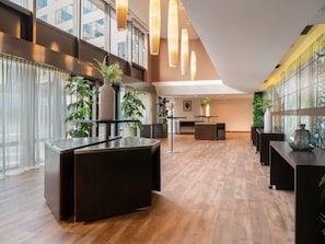 Un moderno vestíbulo de hotel con mostrador de recepción, zonas de estar y ventanas amplias.