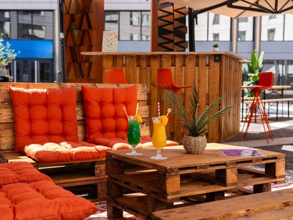 A wooden outdoor seating area with cushioned benches and a table.