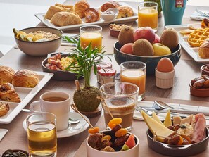 A breakfast buffet with various pastries, fruits, and beverages.