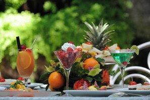A table set with various drinks, fruits, and a pineapple centerpiece. - Hotel Giulio Cesare (Rome)