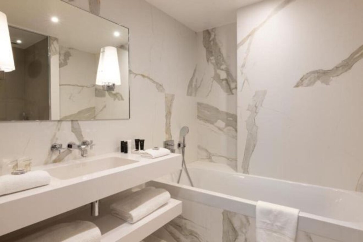 A bathroom with two sinks, a bathtub, and a large mirror.
