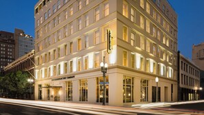 A multi-story hotel with a classic architectural design, featuring a prominent entrance and illuminated signage.