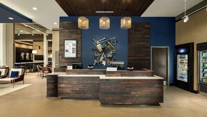 A hotel lobby with a reception desk, seating area, and a wall-mounted sculpture of musical instruments.