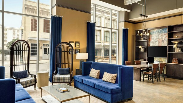 A modern hotel lobby with a blue sofa, a coffee table, and a bookshelf.
