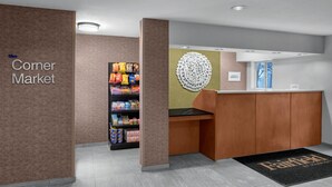 Un espace d’accueil avec une enseigne indiquant un « petit magasin de proximité », un présentoir à collations et un comptoir d’accueil.