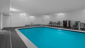 Une piscine dotée d’une terrasse carrelée, d’un vestiaire et d’un petit espace détente avec des tables et des chaises.
