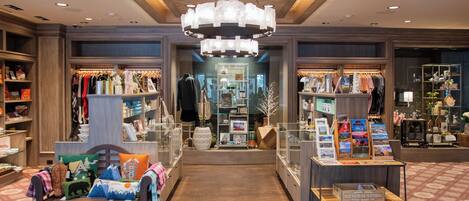 Vestíbulo de un hotel boutique con una zona de estar central, un candelabro y diferentes mostradores de venta al por menor.