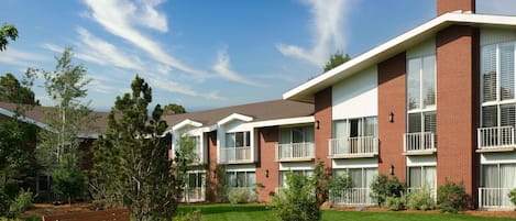 A multi-story residential building with brick exterior, large windows, and a well-maintained lawn.