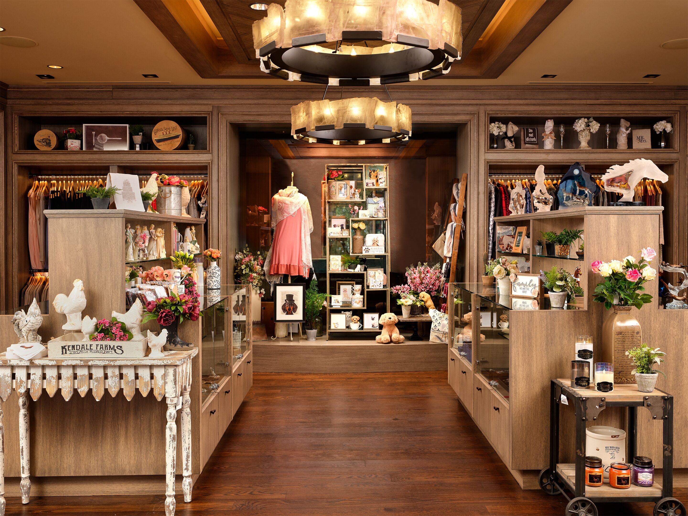 A boutique store with wooden shelves, a central display with a mannequin, and a variety of items including candles and decorative objects.