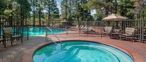 A circular pool with a brick border, surrounded by lounge chairs and a fence.
